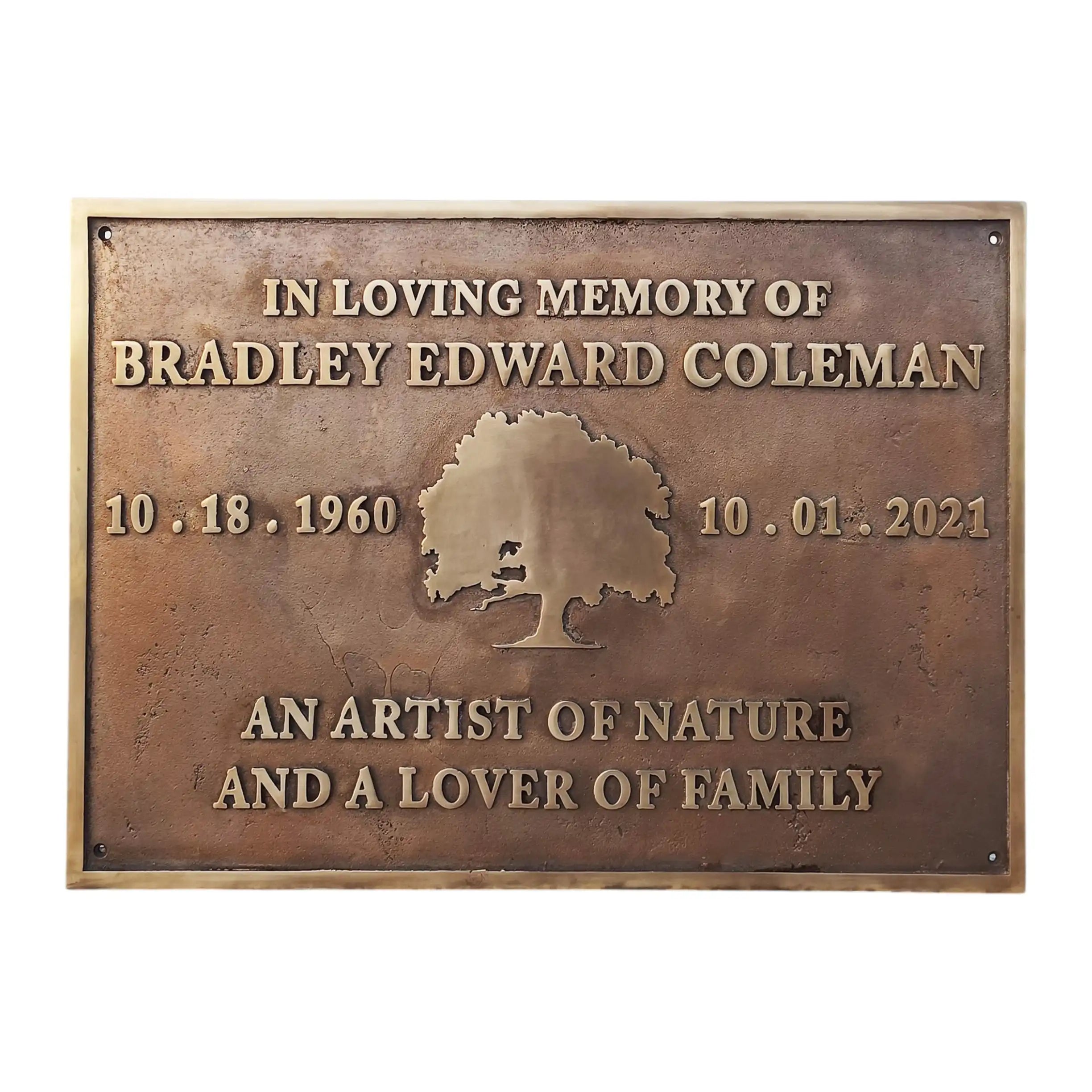 Bronze/brass memorial plaque with engraved text and tree design on a white background
