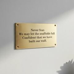 Brass plaque with motivational quote on a gray wall