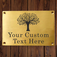 Brass plaque with tree design and customizable text engraving on a wooden background