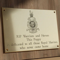 Memorial plaque dedicated to Royal Marines on a wooden background