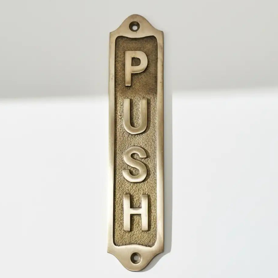 Brass 'PUSH' door plate on a white background