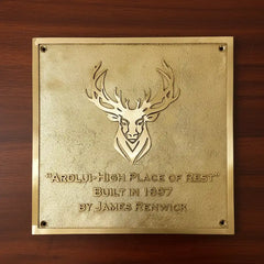 Brass address plaque with custom logo | Gold plaque with deer emblem and text on a wooden background 