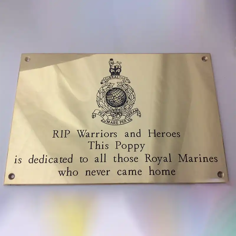 Brass memorial plaque with custom engraving dedicated to Royal Marines with text and emblem on a gold background