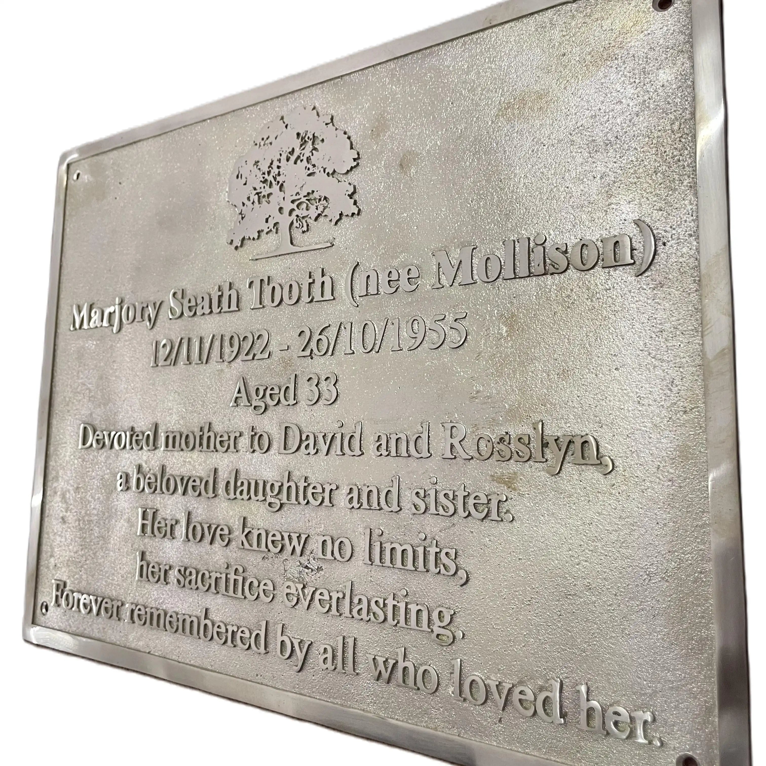 Brass plaque with engraved text and a tree design on a white background