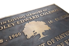 Memorial plaque with engraved text and tree silhouette on a white background