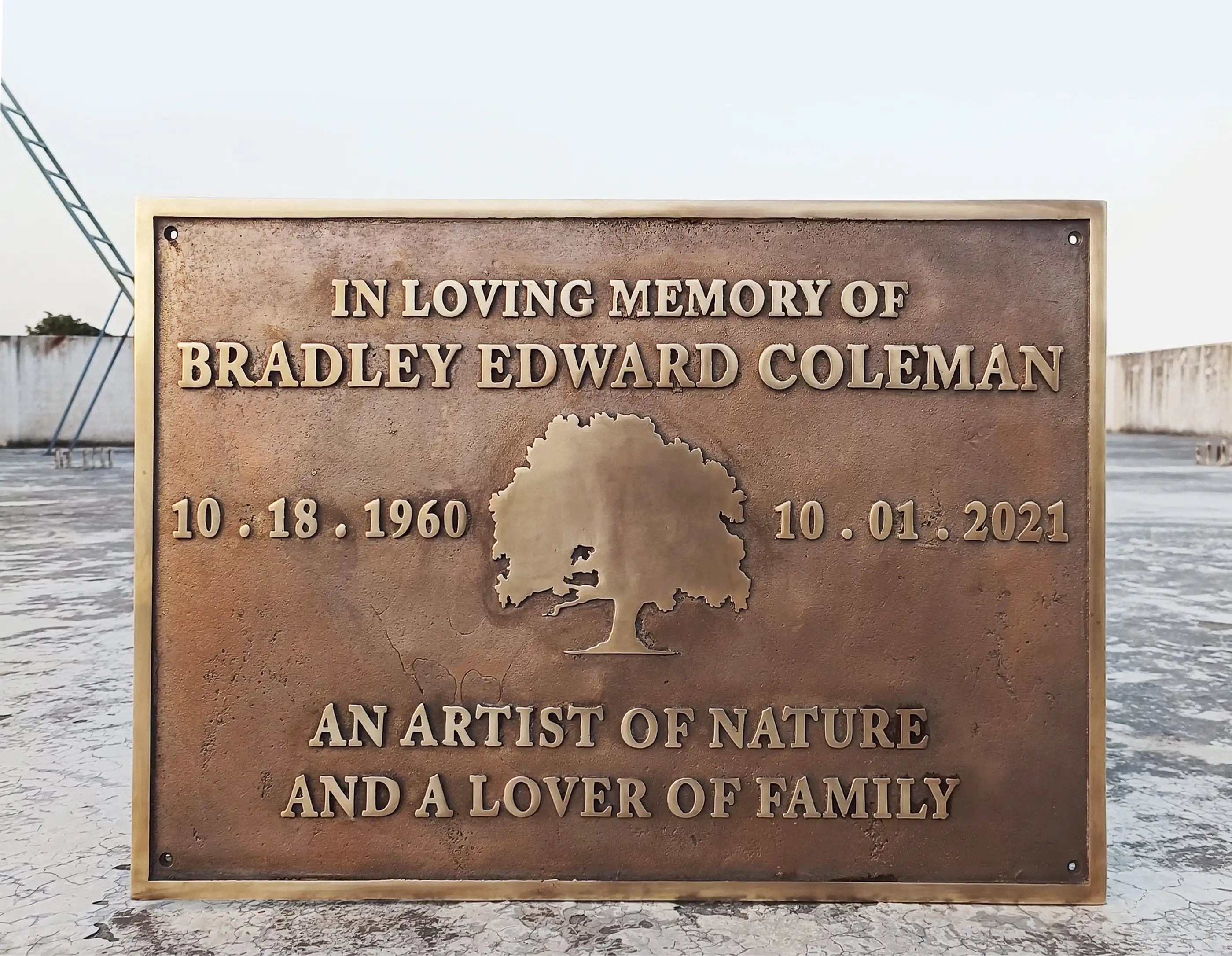 Bronze plaque commemorating Bradley Edward Coleman with a tree design and text about his life.