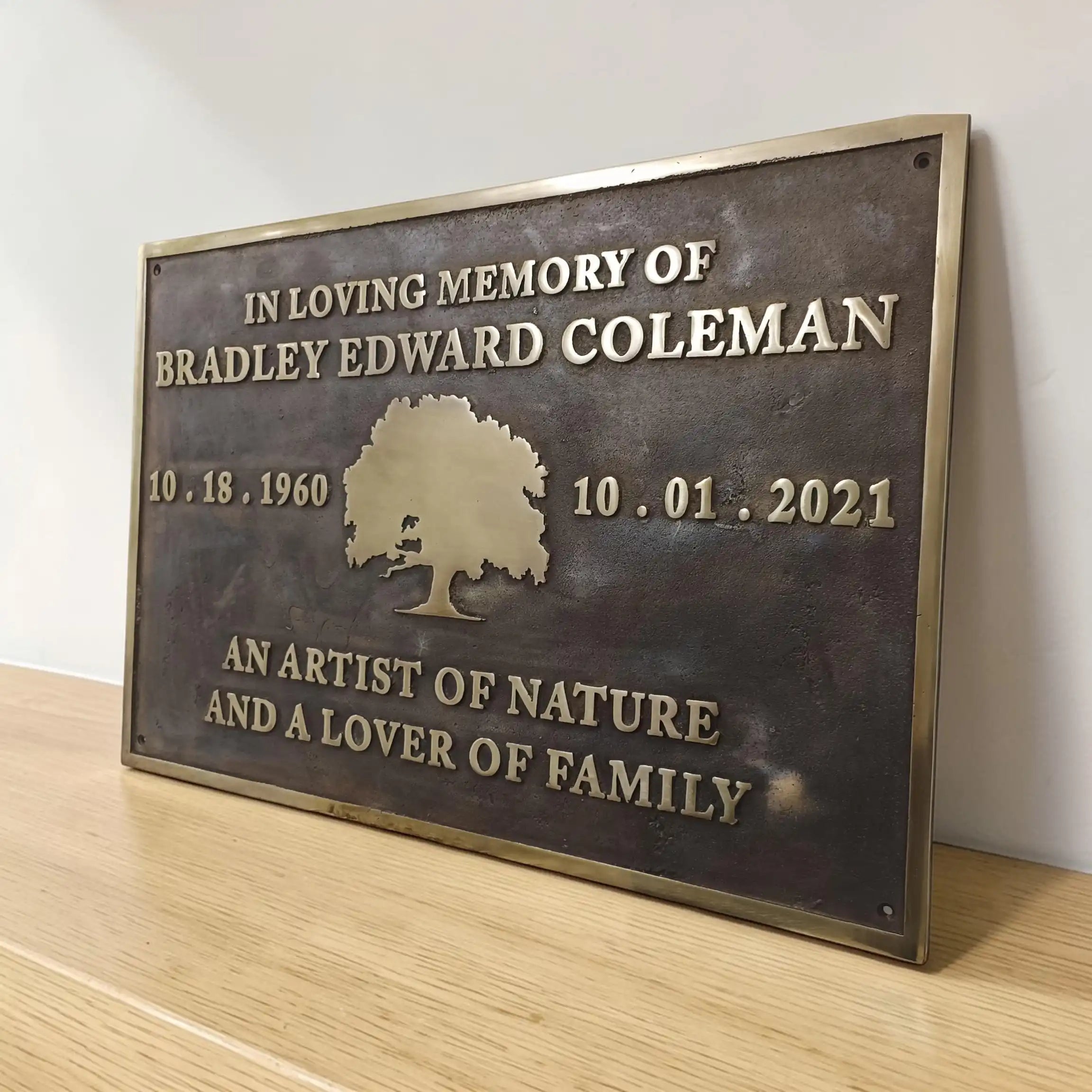 Brass Memorial plaque bronze color on a wooden surface with a white background