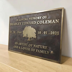 Brass Memorial plaque bronze color on a wooden surface with a white background
