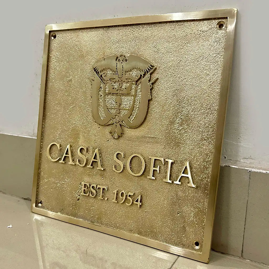 Brass gold  finish brass name plaque with the 'Casa Sofia' logo and establishment year on a gray wall.