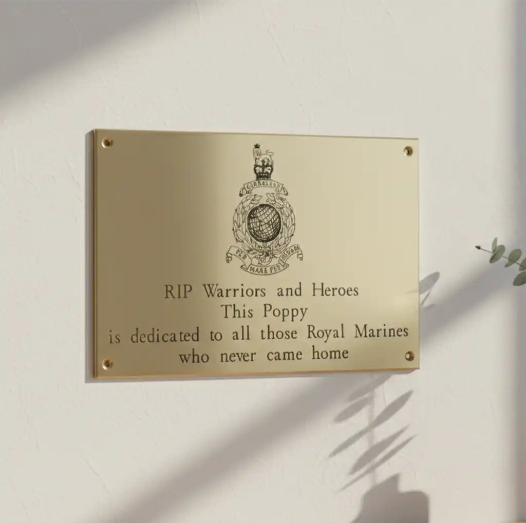 Brass plaque with text and Royal Marines emblem on a light background