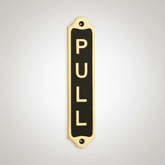 Decorative brass door sign with 'PULL' text on a light gray background