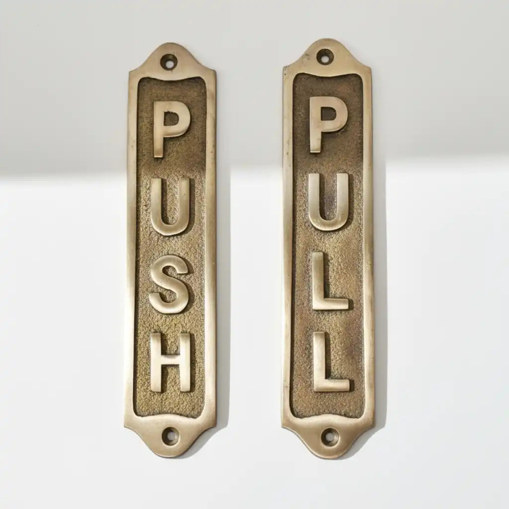 Two brass door signs with 'PUSH' and 'PULL' text on a white background