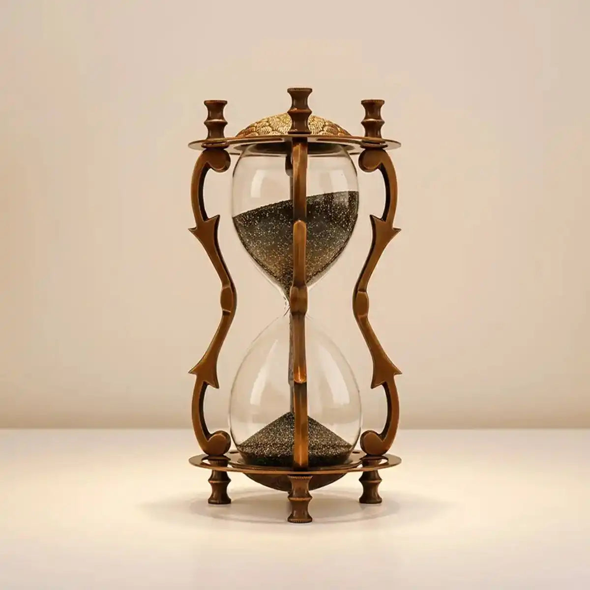 Decorative hourglass with bronze frame and glass bulbs on a beige background