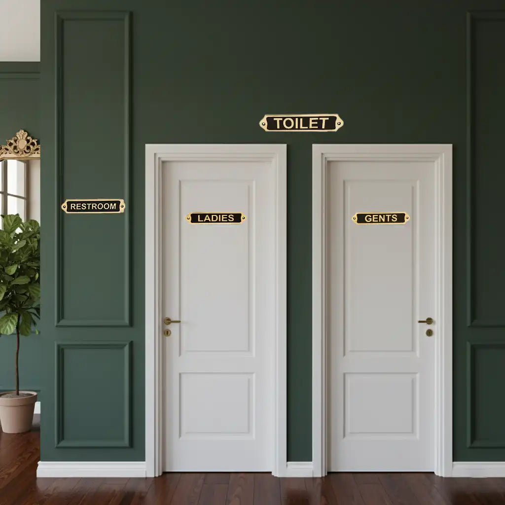 Premium Brass Restroom Door Sign Set  Two white doors labeled 'Ladies' and 'Gents' on a green wall.