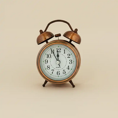 Vintage-style alarm clock with brass finish on a beige background