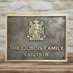 Engraved brass plaque in bronze color on a wooden surface.
