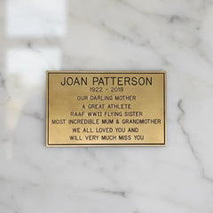 Personalized brass memorial plate—gold plaque with engraved text on a marble background
