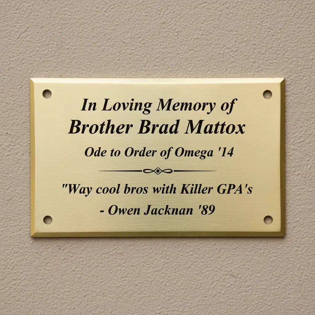 Small brass memorial nameplate—gold plaque with engraved text on a beige wall