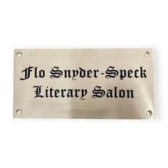 Brass plaque with black text 'Flo Snyder-Speck Literary Salon' on a white background