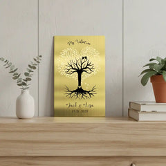 Solid brass engraved sign with a tree design on a wooden shelf with plants and books.
