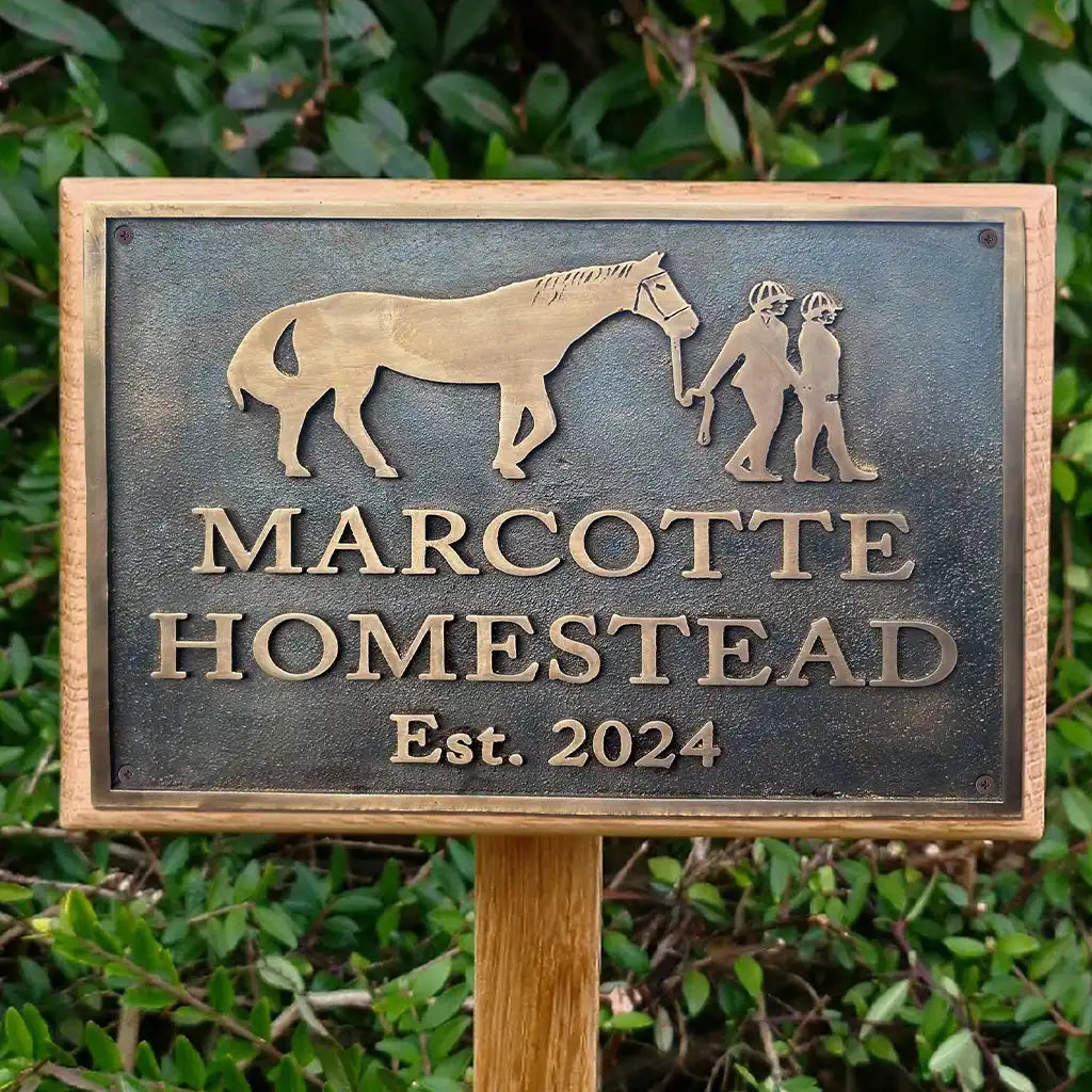 Personalized bronze plaque address sign with horse and person silhouette, 'Marcotte Homestead Est. 2024', against a green leafy background