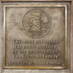 Bronze plaque with engraved text and logo on a stone wall, memorial bronze plaque