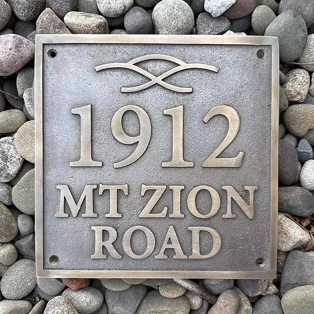 Bronze address plaque with house number on a pebble background