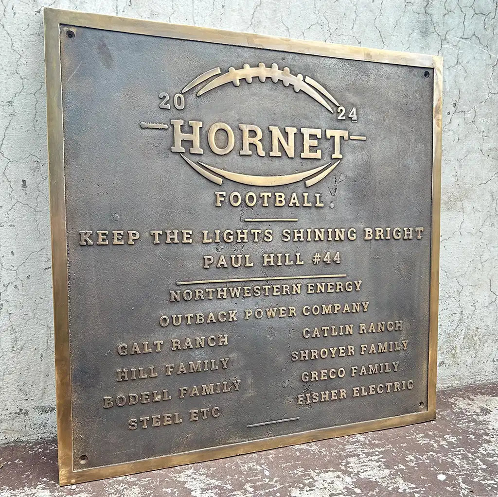 Bronze plaque with 'Hornet Football' design and text on a textured wall background
