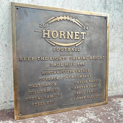 Bronze plaque with 'Hornet Football' design and text on a textured wall background