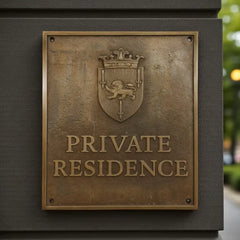 Bronze plaque with a coat of arms and 'Private Residence' text on a dark background. Personalised bronze house nameplate