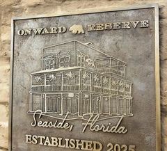 custom cast bronze plaque with architectural design and text on a stone wall