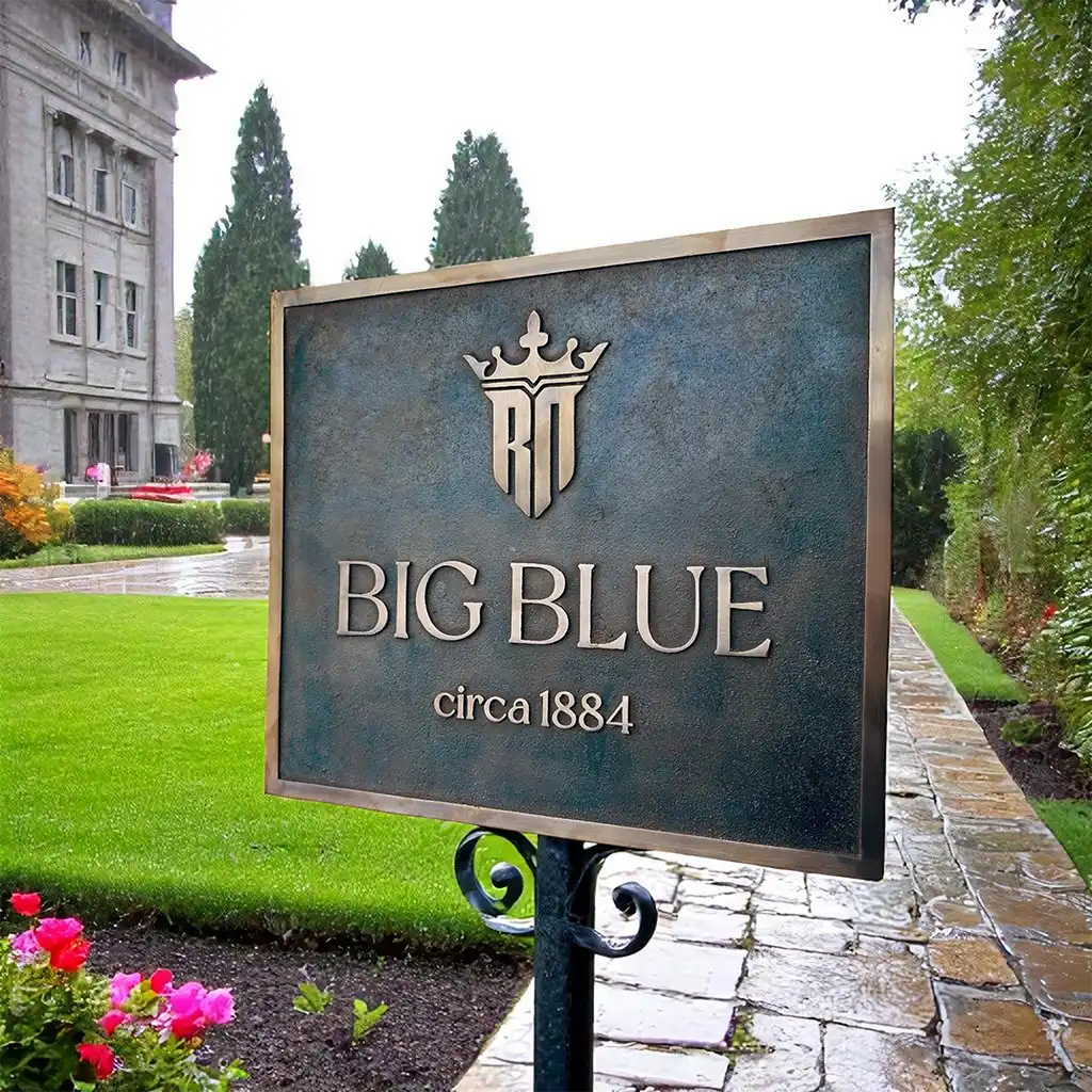 Architectural bronze plaque, Sign for 'BIG BLUE' with a building and garden in the background