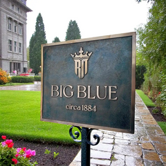 Architectural bronze plaque, Sign for 'BIG BLUE' with a building and garden in the background