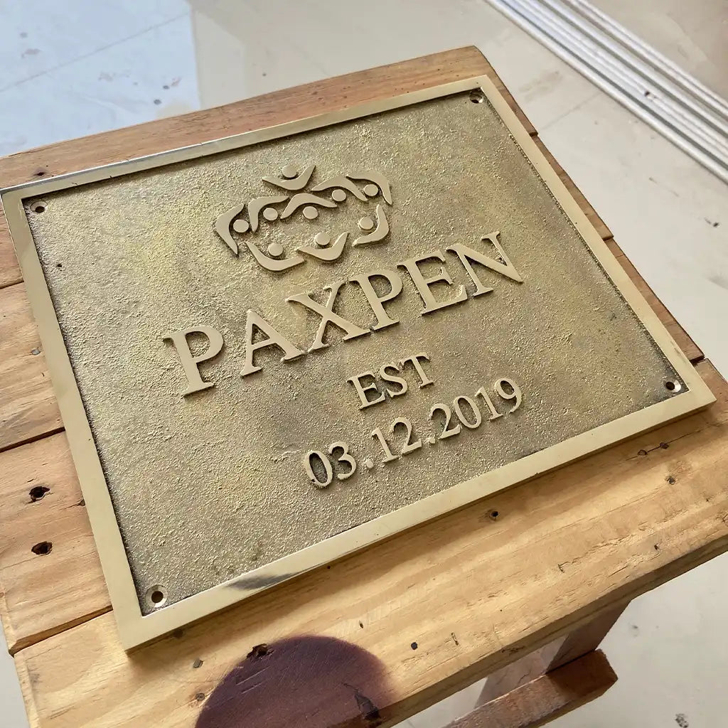 Engraved brass address plate—a metal plaque with branding and establishment date on a wooden surface