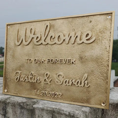 Decorative engraved brass nameplate with text and names on a stone ledge.
