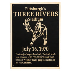 A black brass plaque with gold text, featuring an image of a baseball player and the text