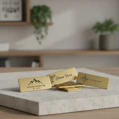 Gold name-engraved brass label tag with engraved designs on a marble surface