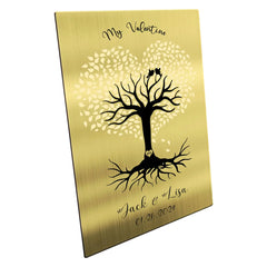 A gold-colored brass plate with an engraved design of a tree and hearts, with customizable text for a personalized gift.