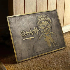 Personalized memorial bronze plaque with a stylized portrait and text on a wooden surface