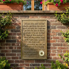 Decorative bronze tribute plaque with custom text on a brick wall with plants above