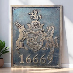 Cast bronze plaque with a coat of arms and numbers '16669' on a white wall.