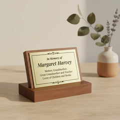 Brass plate for urn memorial—a memorial plaque on a wooden stand with a vase of flowers in the background.