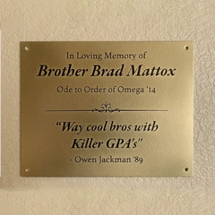 Custom brass memorial plate—gold plaque with engraved text on a beige wall