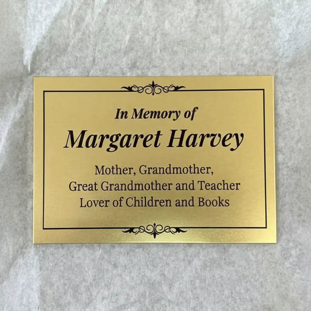 Brass memorial plate custom with engraved text on a gray background