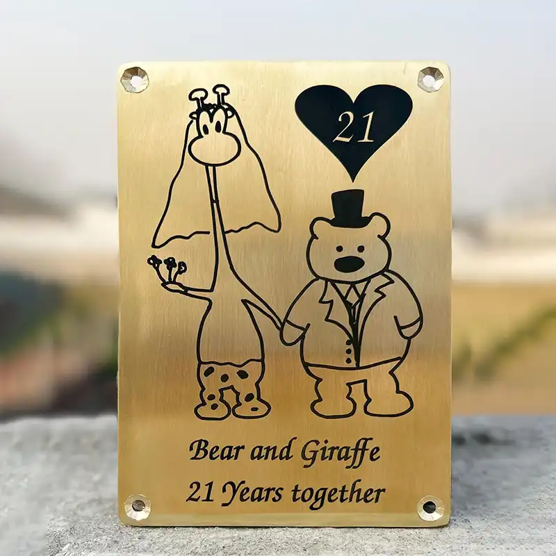 Engraved brass plaque with bear and giraffe illustration and '21 Years together' text on a blurred background