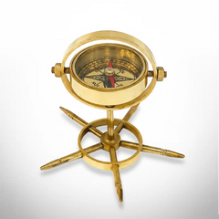 Brass gimbal compass with decorative stand on a white background