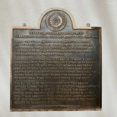 Bronze plaque with historical text on a white wall