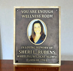 Memorial plaque a portrait and text on a wooden surface.