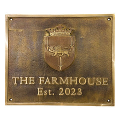 A rectangular brass address plaque with a coat of arms emblem and the text engraved on it.