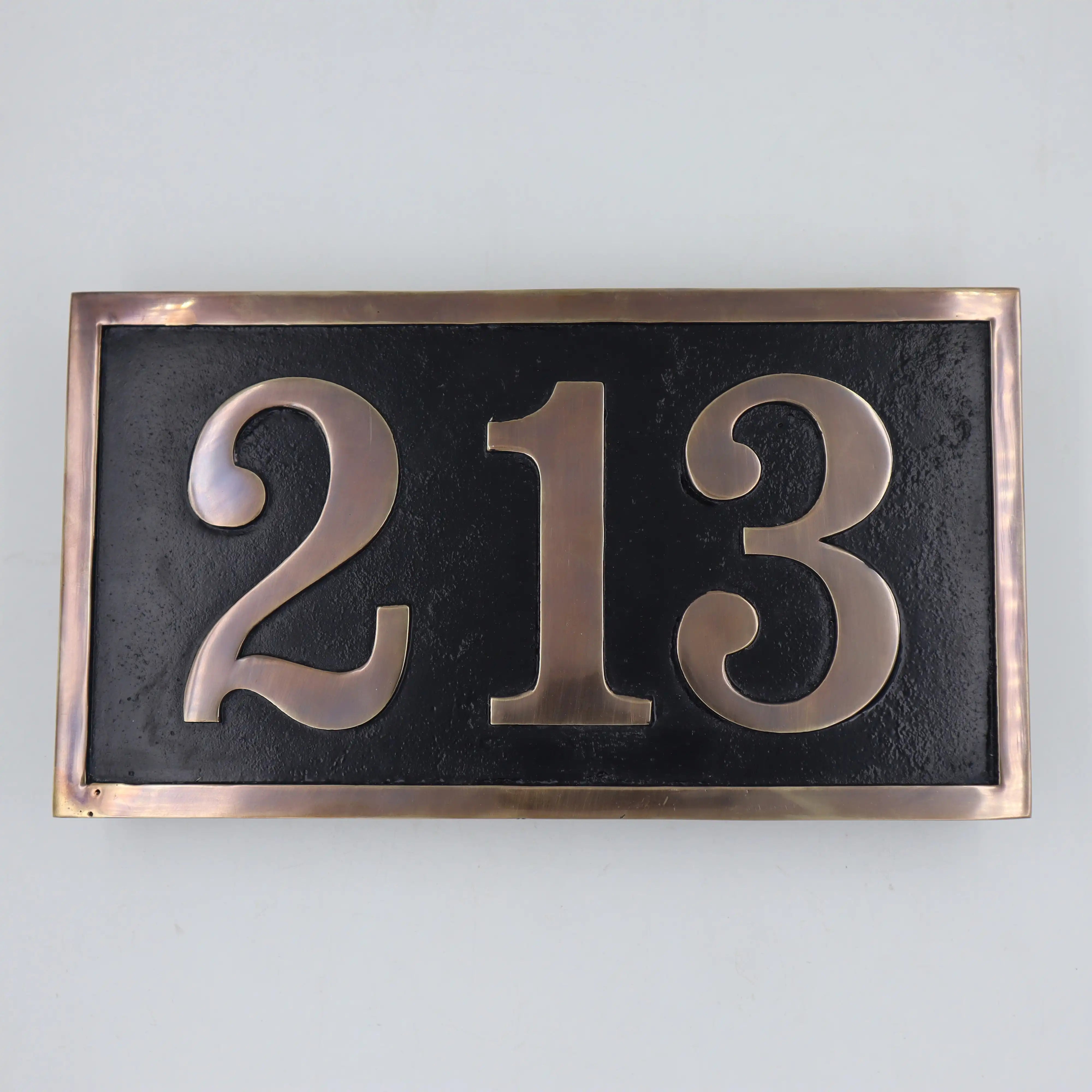 Brass house number plate with '213' on a black background with bronze border